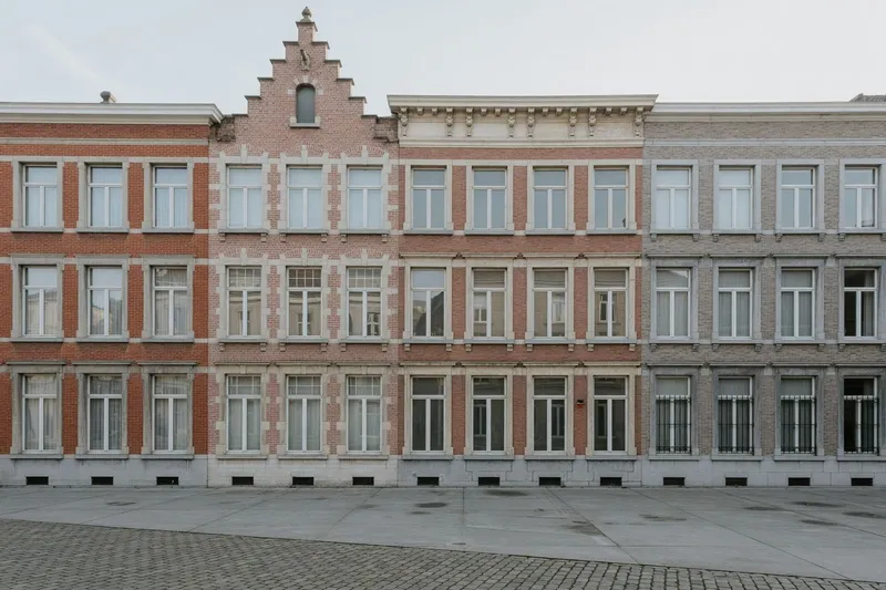 Illustration : une rangée de maisons de maître bruxelloises aux façades de brique et de pierre.