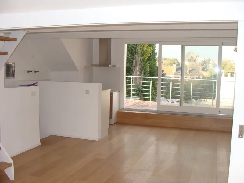 Étage sous toiture achevé : parquet en chêne, cuisine blanche et baie coulissante vers la terrasse.