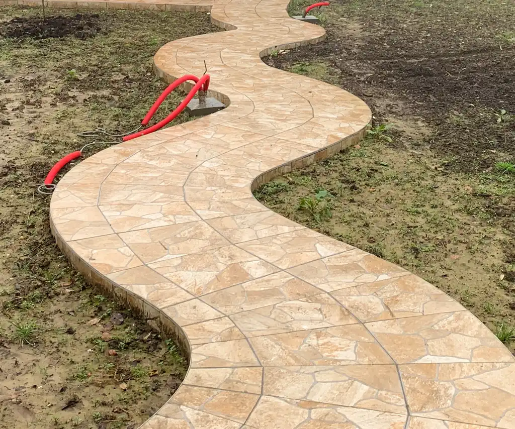 Terre nue avec un sentier sinueux en pierre naturelle et des attentes visibles.