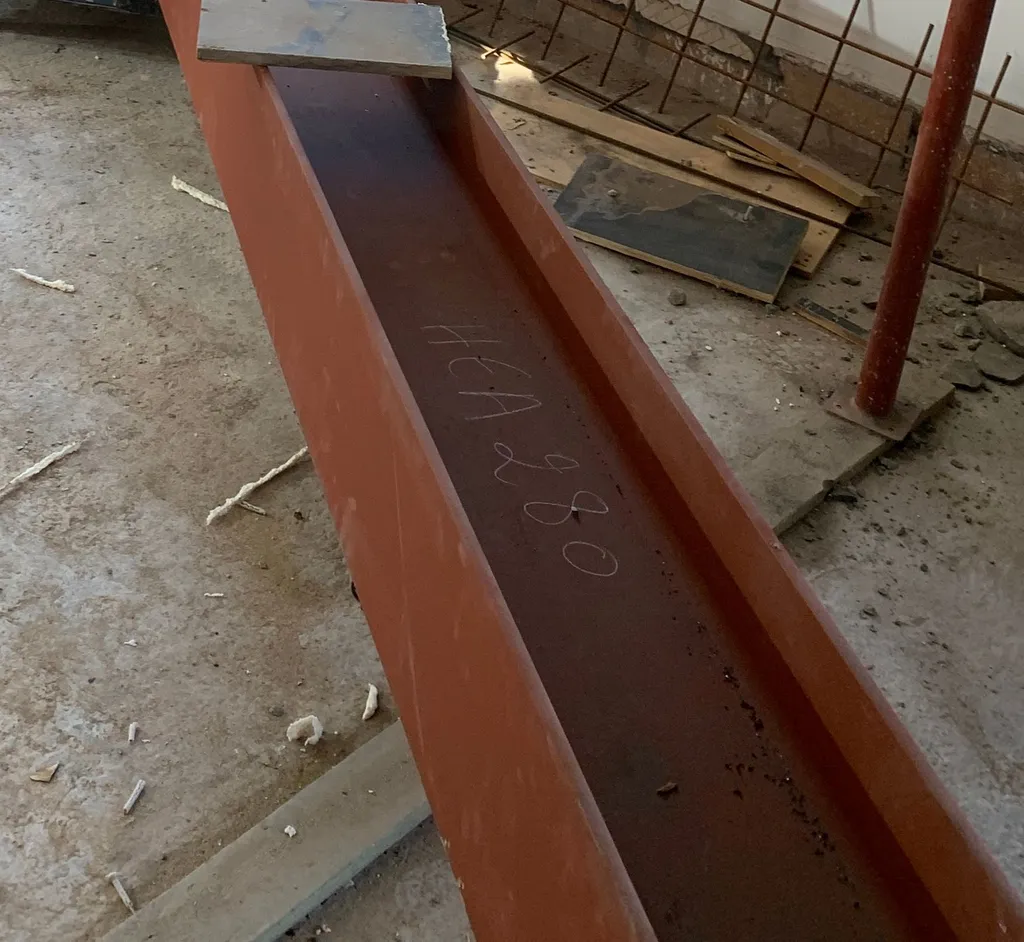 Poutre en acier portant la mention à la craie HEA 280, prête à être posée.
