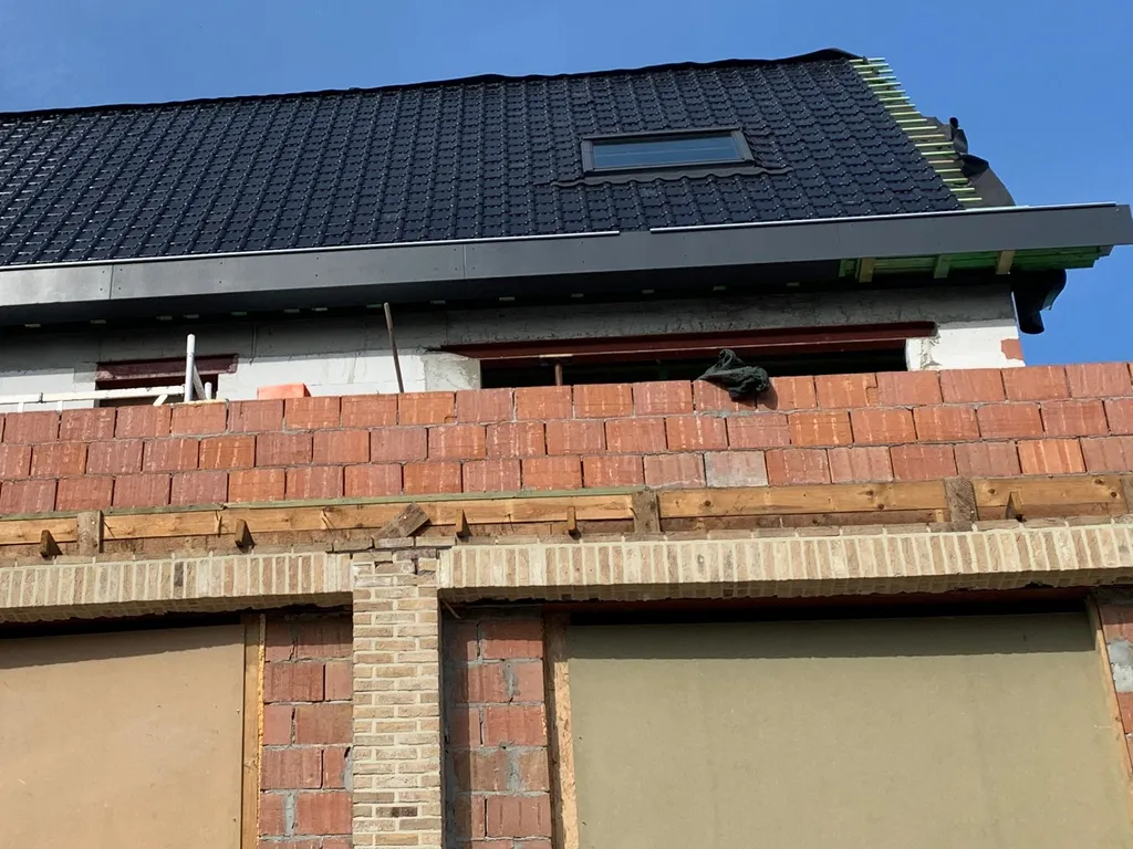 Nouvelle toiture en tuiles avec fenêtre de toit et profil de rive en aluminium.