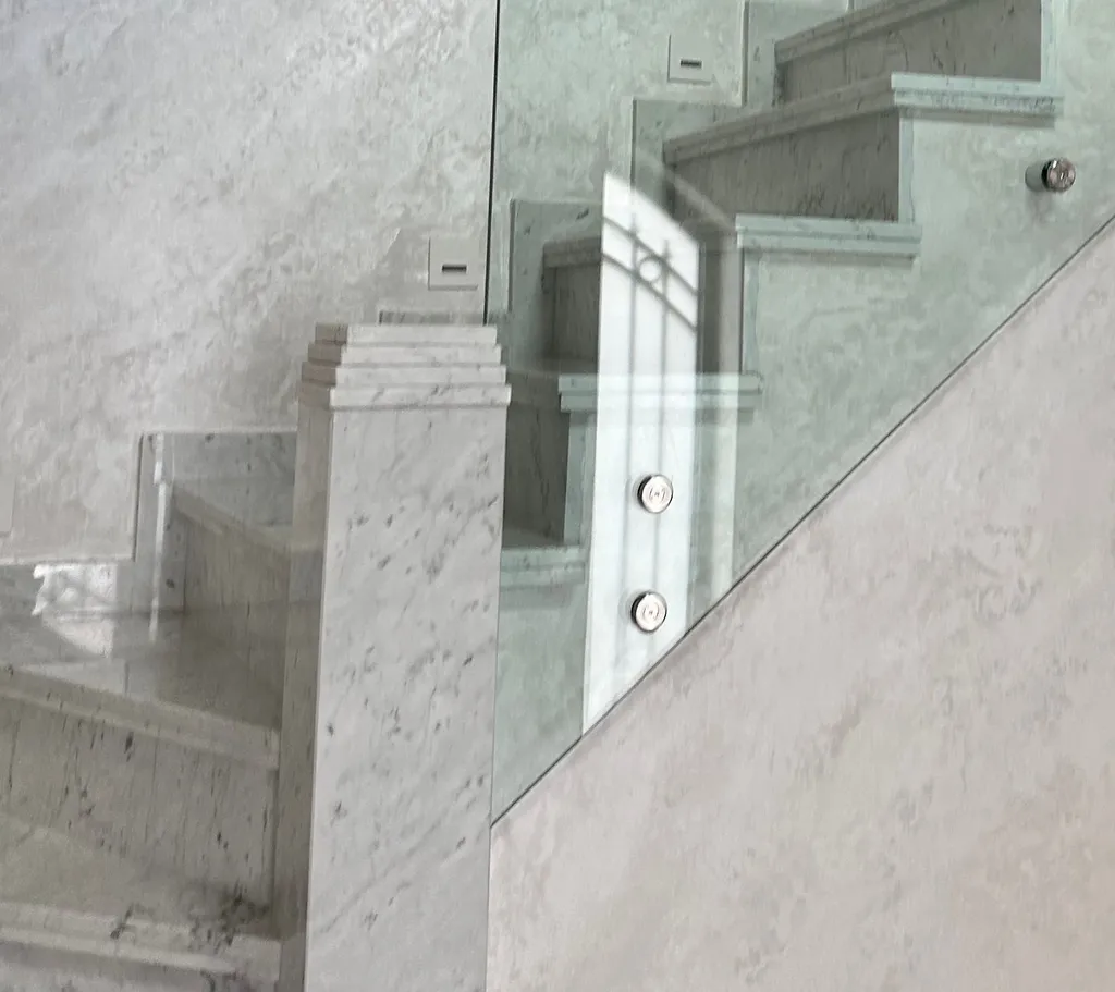 Escalier en marbre fini, garde-corps en verre sur fixations ponctuelles inox.