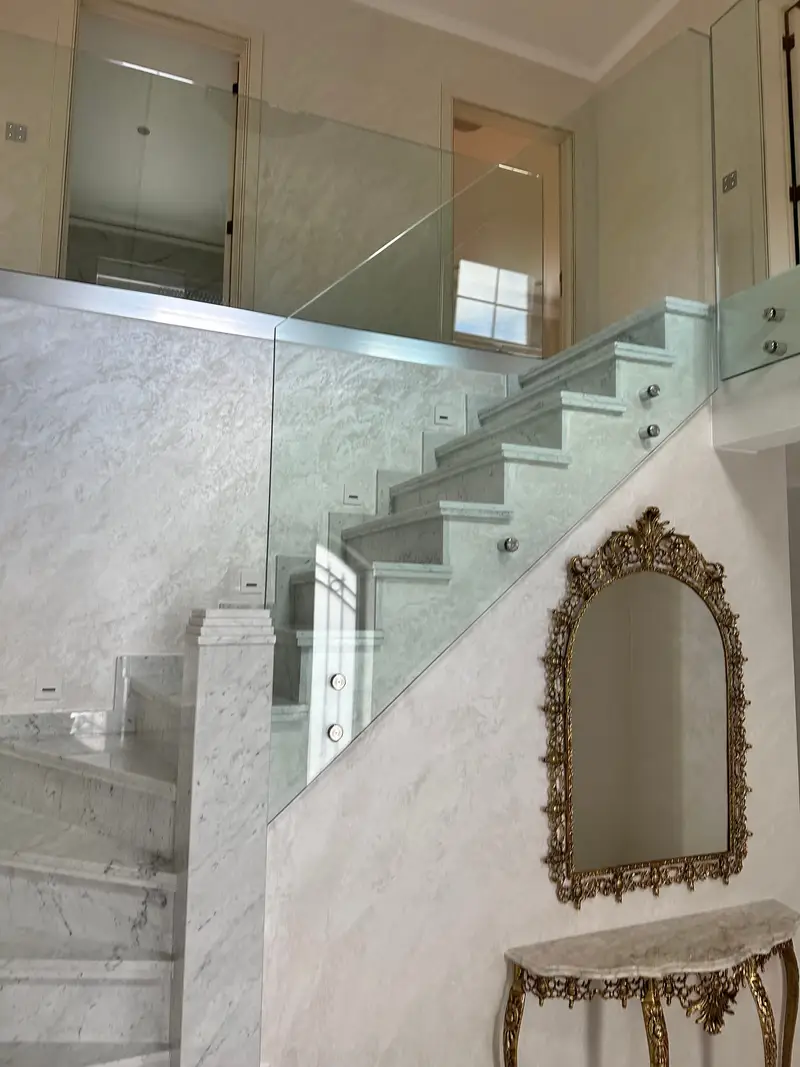 Escalier en marbre fini, garde-corps en verre sur fixations ponctuelles inox.